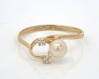 May include: A gold ring with a pearl and two small diamonds. The ring has a delicate, curved design.