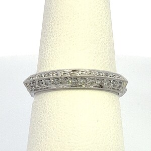 May include: A silver band ring with a row of small diamonds set in a delicate design.