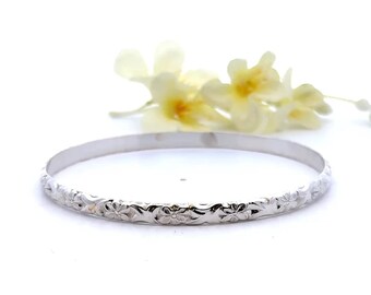 May include: A silver bangle bracelet with a floral design. The bracelet is made of polished silver and has a delicate floral pattern.