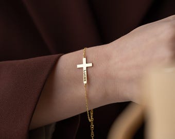 May include: Gold cross bracelet with the name "Lucas" engraved on the cross.