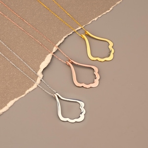 May include: Three necklaces with pendant designs in silver, rose gold, and gold. Each pendant has a teardrop shape with a scalloped edge, suspended from a delicate chain. The necklaces are displayed on a neutral background.