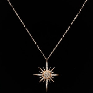 May include: A gold necklace with a starburst pendant set with clear stones.