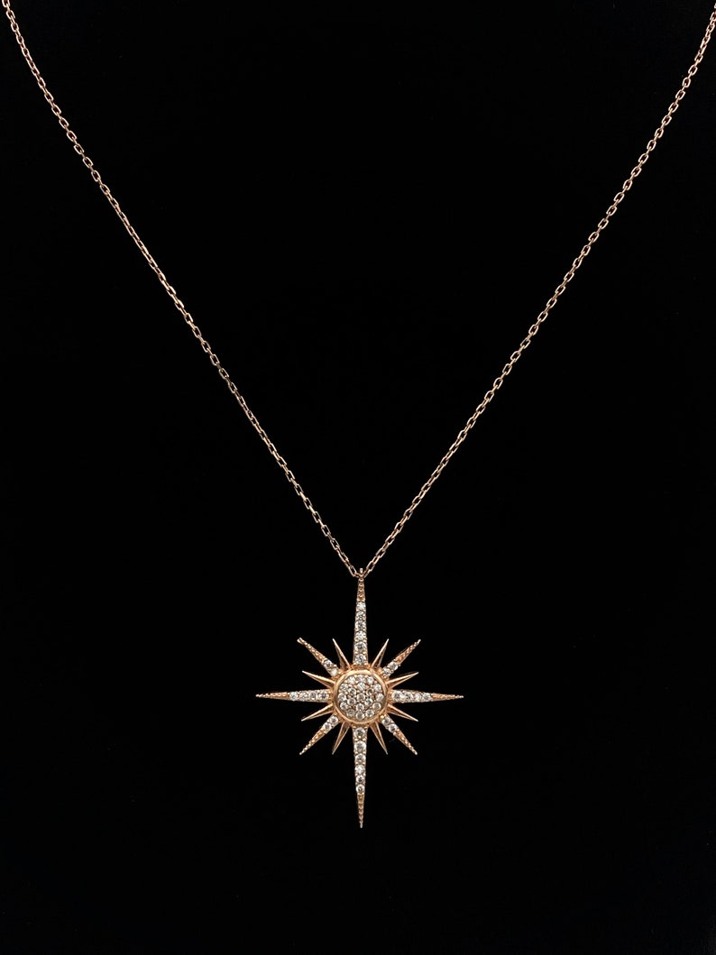 May include: A gold necklace with a starburst pendant set with clear stones.