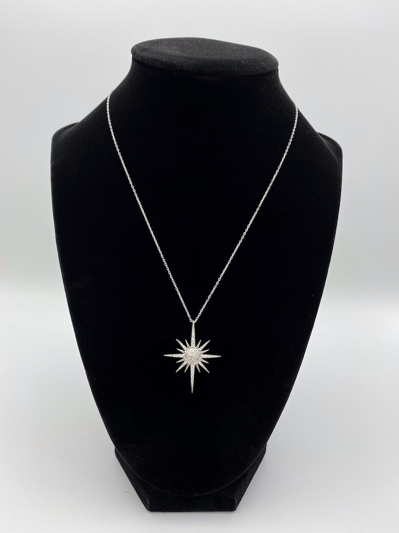 May include: A silver necklace with a starburst pendant set with clear cubic zirconia stones.