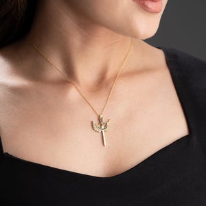 May include: A gold necklace with a pendant featuring a sword with wings. The pendant is detailed and intricate.