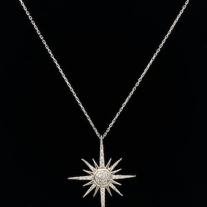 May include: A silver necklace featuring a starburst pendant set with clear cubic zirconia stones.