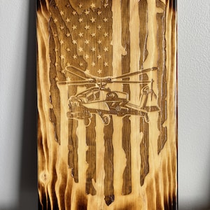 May include: A wooden sign with a burnt finish features a laser-engraved American flag with a helicopter in the center.