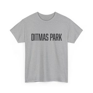 May include: A heather gray t-shirt with the text "DITMAS PARK" printed in black block letters across the chest. The shirt has short sleeves and a crew neck.