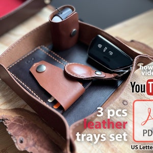 May include: A set of three brown leather trays, with one tray containing a black key fob, a brown leather key holder, and a brown leather wallet. The image also includes text that says "3 pcs leather trays set", "how to video", "You Tube", "PDF", and "US Letter & A4".
