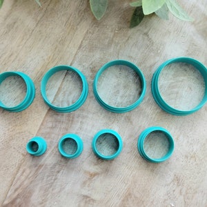May include: Set of nine teal-colored plastic cookie cutters in various sizes and shapes, including circles and a cone shape.