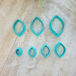 May include: Set of eight teal blue plastic leaf-shaped cookie cutters of varying sizes.