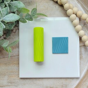 May include: Two silicone texture stamps for baking and crafting. One is a bright green roller with a wavy pattern. The other is a square blue stamp with a wavy pattern.