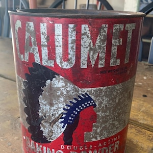 May include: Vintage Calumet Baking Powder tin. The red and white tin features the word "CALUMET" in large letters and an illustration of a Native American chief. The net weight is 10 lbs.