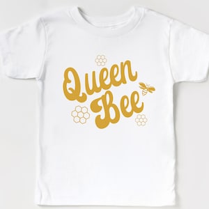 May include: White t-shirt with a gold graphic that says "Queen Bee" with a bee and honeycomb designs.