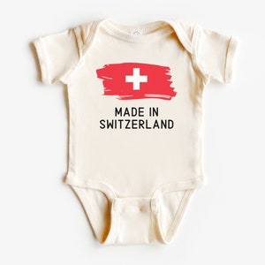 May include: A white baby onesie with a red and white Swiss flag and the text "MADE IN SWITZERLAND".