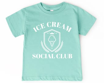 May include: A light blue t-shirt with a white graphic design. The graphic features a shield with an ice cream cone and the text "Ice Cream Social Club".