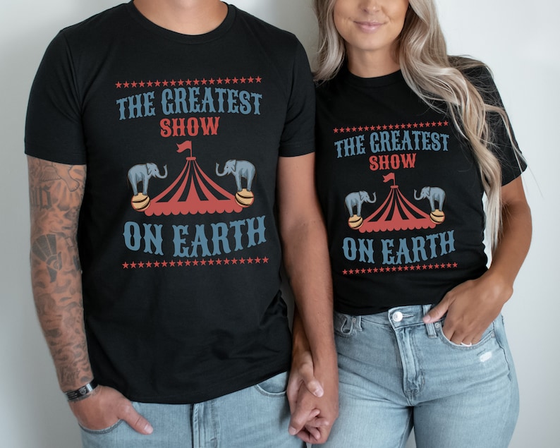 May include: A matching set of black t-shirts with a circus theme. The shirts feature a red and white striped tent with two elephants balancing on balls. The text on the shirts reads "The Greatest Show On Earth".
