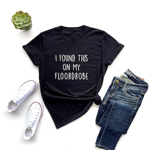 Puede incluir: Camiseta negra con texto blanco que dice "I found this on my floordrobe".