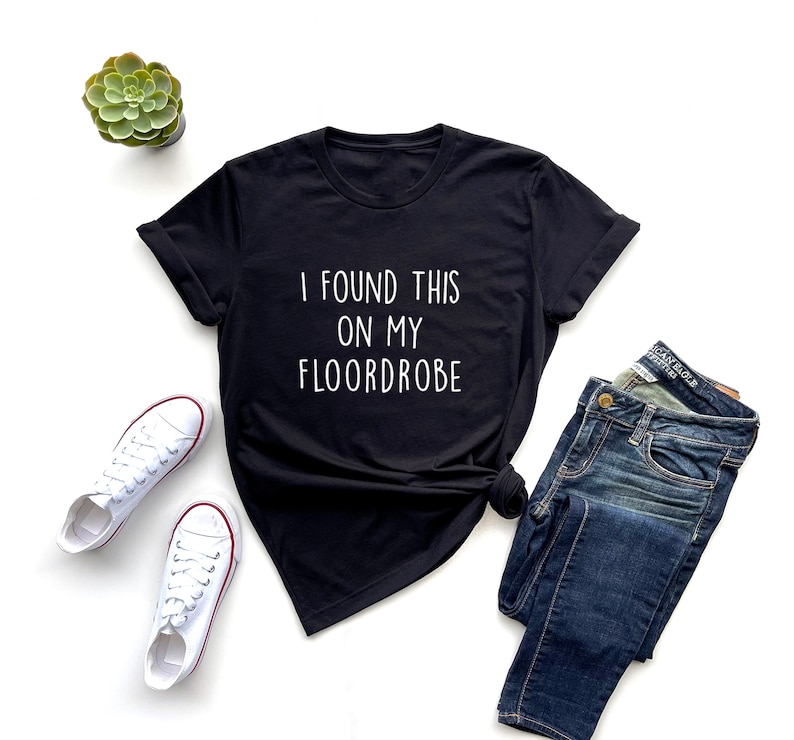 Puede incluir: Camiseta negra con texto blanco que dice "I found this on my floordrobe".