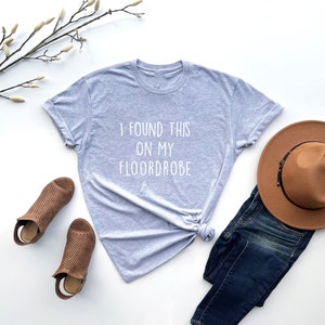 Puede incluir: Una camiseta gris con el texto "I found this on my floordrobe" impreso en blanco.