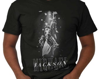 May include: Black t-shirt featuring a black and white image of Michael Jackson performing on stage, holding a microphone and raising his fist. The name "MICHAEL JACKSON" is printed in white below the image.