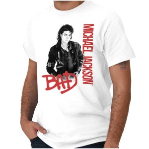 May include: White t-shirt featuring a black and white image of Michael Jackson in a black jacket. The word "BAD" is in red, stylized text below the image, with "MICHAEL JACKSON" in red text on the right side.