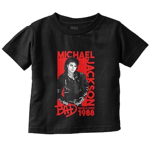 May include: Black t-shirt featuring a red graphic of Michael Jackson with the text "MICHAEL JACKSON" and "BAD WORLD TOUR 1988". The image shows a portrait of Michael Jackson in a black leather jacket.