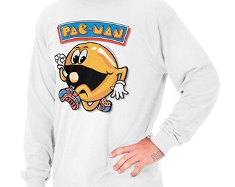 May include: White long-sleeve shirt featuring a Pac-Man graphic. The graphic includes the Pac-Man logo and a cartoon Pac-Man character in yellow, black, and blue. The shirt is a classic, casual style.