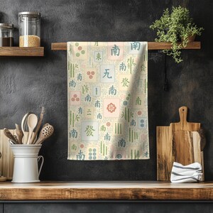 Soft pastel Mahjong tile tea towel hanging against a dark textured kitchen wall