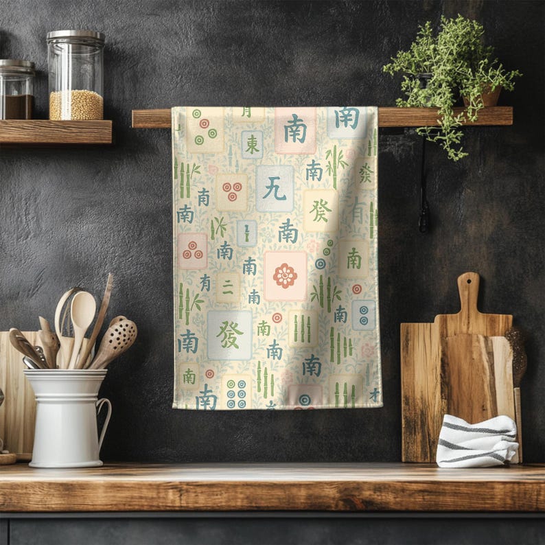 Soft pastel Mahjong tile tea towel hanging against a dark textured kitchen wall