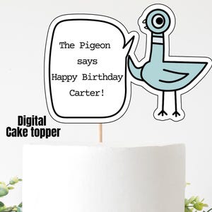 May include: A white cake with a digital cake topper featuring a cartoon pigeon and the text "The Pigeon says Happy Birthday Carter!". The cake is on a wooden cake stand with greenery.
