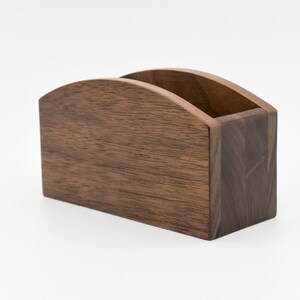 May include: A dark brown wooden organizer with a curved top and a rectangular base. The organizer is made of walnut wood and has a natural finish.