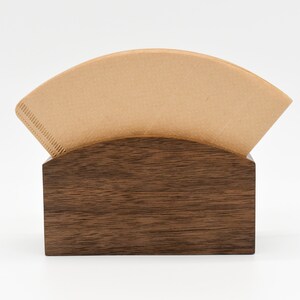 May include: A brown wooden coffee filter holder with a single brown paper coffee filter inside.