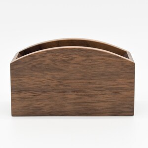 May include: A dark brown wooden box with a curved top. The box is made of wood with a natural grain pattern.