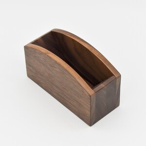 May include: A wooden coffee filter holder with a curved top and a rectangular base. The holder is made of dark brown wood.