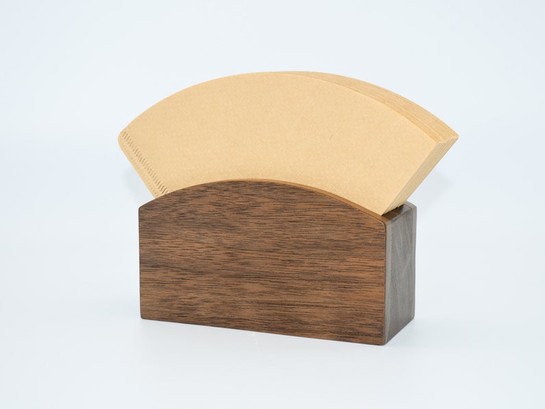May include: A wooden coffee filter holder with a brown paper filter inside. The holder is made of dark wood with a natural grain pattern.