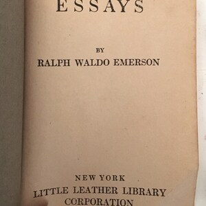 May include: Open book with the title "ESSAYS" at the top, followed by "BY RALPH WALDO EMERSON." Below, it reads "NEW YORK LITTLE LEATHER LIBRARY CORPORATION." The pages are aged with a tan color.