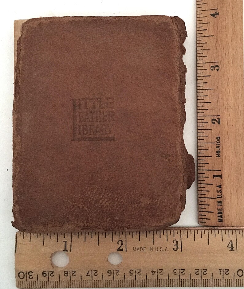 May include: A small, brown leather-bound book with the embossed text "LITTLE LEATHER LIBRARY." The book is approximately 3 inches long and 2 inches wide. The edges of the book are rough and worn, suggesting age.