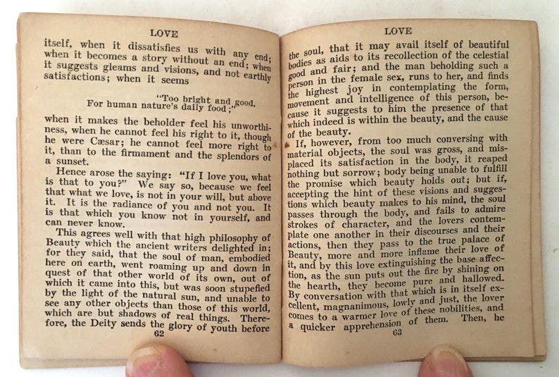 May include: Open book with aged, yellowed pages. The text discusses love and beauty, with the word "LOVE" at the top of each page. The book is open to pages 62 and 63, with text filling the pages.