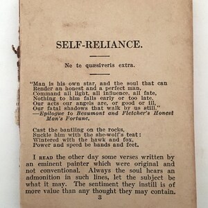 May include: A vintage, rectangular paper with the title "SELF-RELIANCE" in bold, black text. The paper has aged, with a light brown hue and visible wear along the edges. Text from the poem is printed below the title.