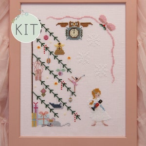 May include: A cross-stitch pattern kit featuring a whimsical Christmas scene with a girl holding a nutcracker, a ballerina, a clock, and a decorated Christmas tree. The kit includes a white fabric, floss, and instructions.