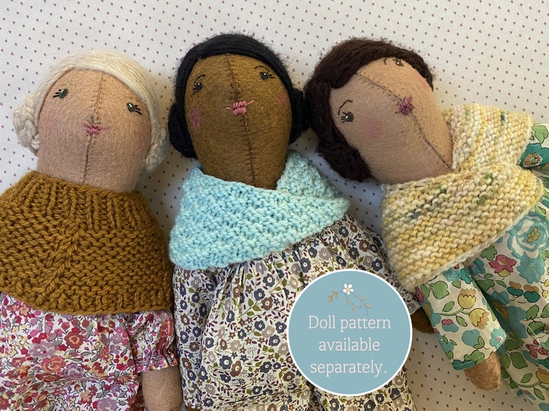 Three handmade dolls wearing handknit doll cowls and shawls.