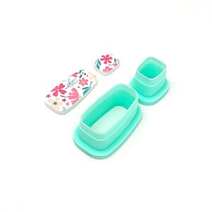 Peut inclure: Ensemble de d&eacute;coupoirs en p&acirc;te polym&egrave;re et pi&egrave;ces en argile &agrave; motifs floraux. Les d&eacute;coupoirs sont de couleur bleu sarcelle clair, de formes rectangulaires et carr&eacute;es. Les pi&egrave;ces d'argile pr&eacute;sentent des fleurs roses et blanches avec des feuilles vertes sur fond blanc.