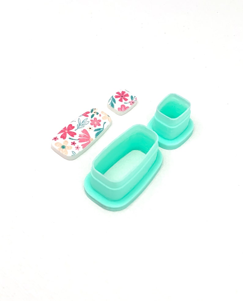 Peut inclure: Ensemble de d&eacute;coupoirs en p&acirc;te polym&egrave;re et pi&egrave;ces en argile &agrave; motifs floraux. Les d&eacute;coupoirs sont de couleur bleu sarcelle clair, de formes rectangulaires et carr&eacute;es. Les pi&egrave;ces d'argile pr&eacute;sentent des fleurs roses et blanches avec des feuilles vertes sur fond blanc.