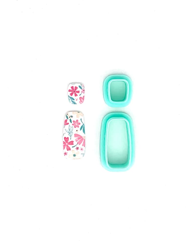 Peut inclure: Deux motifs floraux pour nail art et deux moules &agrave; nail art turquoise sont pr&eacute;sent&eacute;s sur fond blanc. Les motifs de nail art pr&eacute;sentent des fleurs roses et blanches. Les moules sont rectangulaires et carr&eacute;s.