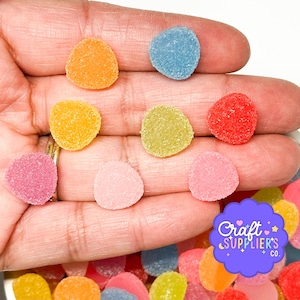 Può includere: Una varietà di caramelle rotonde e colorate nelle tonalità arancione, giallo, blu, rosso, rosa e verde. Le caramelle sono tenute in mano e sembrano essere ricoperte di zucchero. L'immagine include anche un logo per "Craft Suppliers & Co."