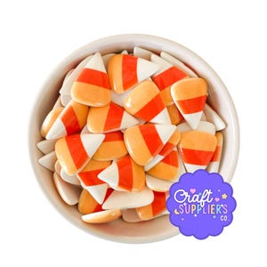 May include: A white ceramic bowl filled with candy corn. The candy corn pieces are white, orange, and yellow. The image also includes a purple sticker with the text "Craft Supplier's Co."