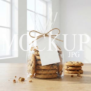 May include: A clear cellophane bag tied with twine, filled with chocolate chip cookies. A blank white tag hangs from the twine. Several cookies are stacked on a wooden surface next to the bag. The cookies are golden brown with chocolate chips.