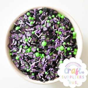 May include: A white ceramic bowl filled with colorful polymer clay sprinkles. The sprinkles include black, green, and lavender shapes, including witch hats, spheres, and rods. The image also includes the text "Craft Suppliers Rus".