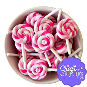 Puede incluir: Un cuenco lleno de numerosos caramelos de espiral rosa y blanco sobre palitos blancos. Los caramelos tienen un diseño en espiral con rayas rosas y blancas alternas. El cuenco es de color rosa claro.